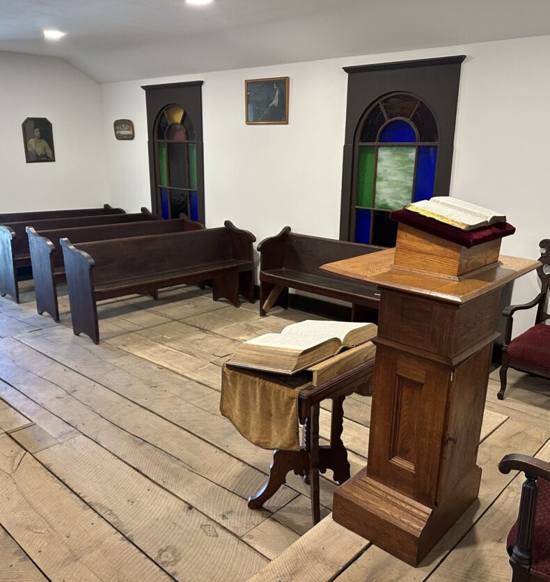 Church Inside Interior of a simple chapel with wooden pews, a lectern with an open Bible, and stained glass windows