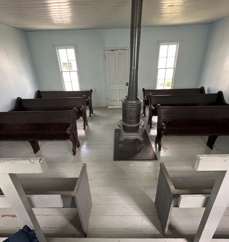 Meeting Room Interior of a simple room with wooden pews and a wood-burning stove in the center