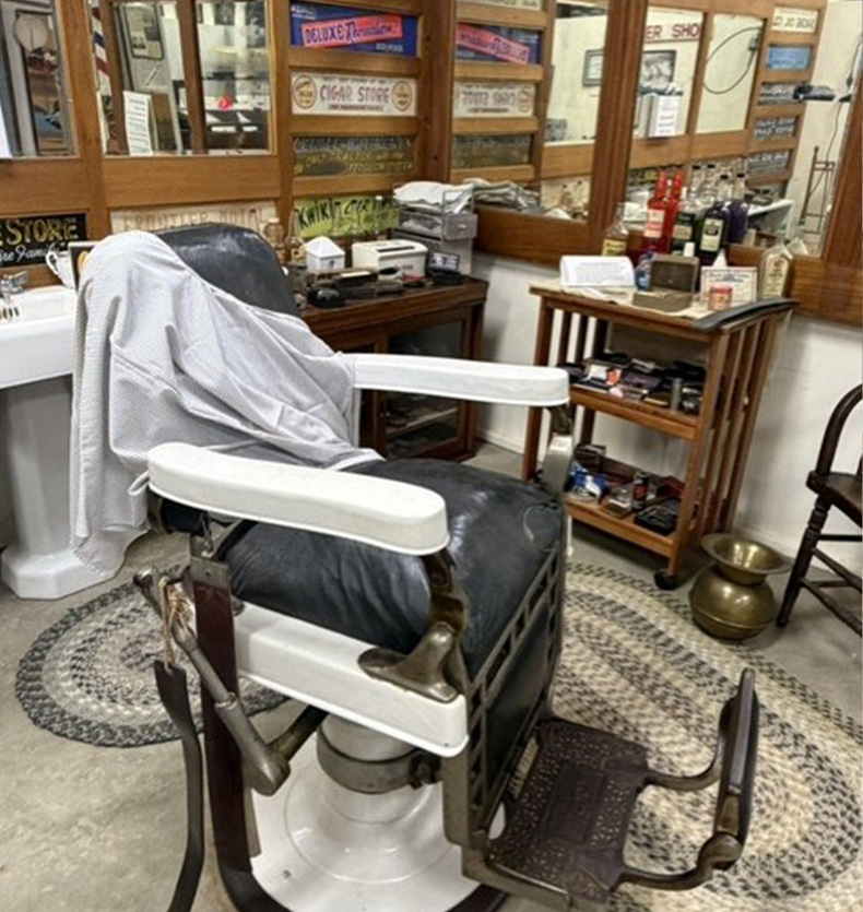 Vintage black leather barber chair in a shop with wood-paneled walls and antique signs