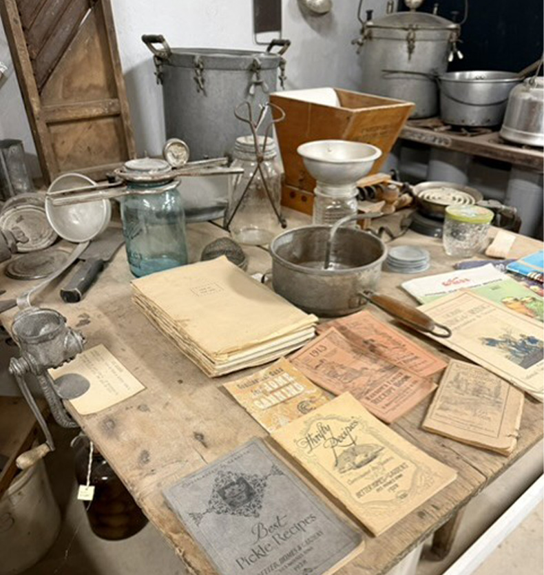 Vintage canning equipment and recipe booklets, including Best Pickle Recipes, on a rustic wooden table
